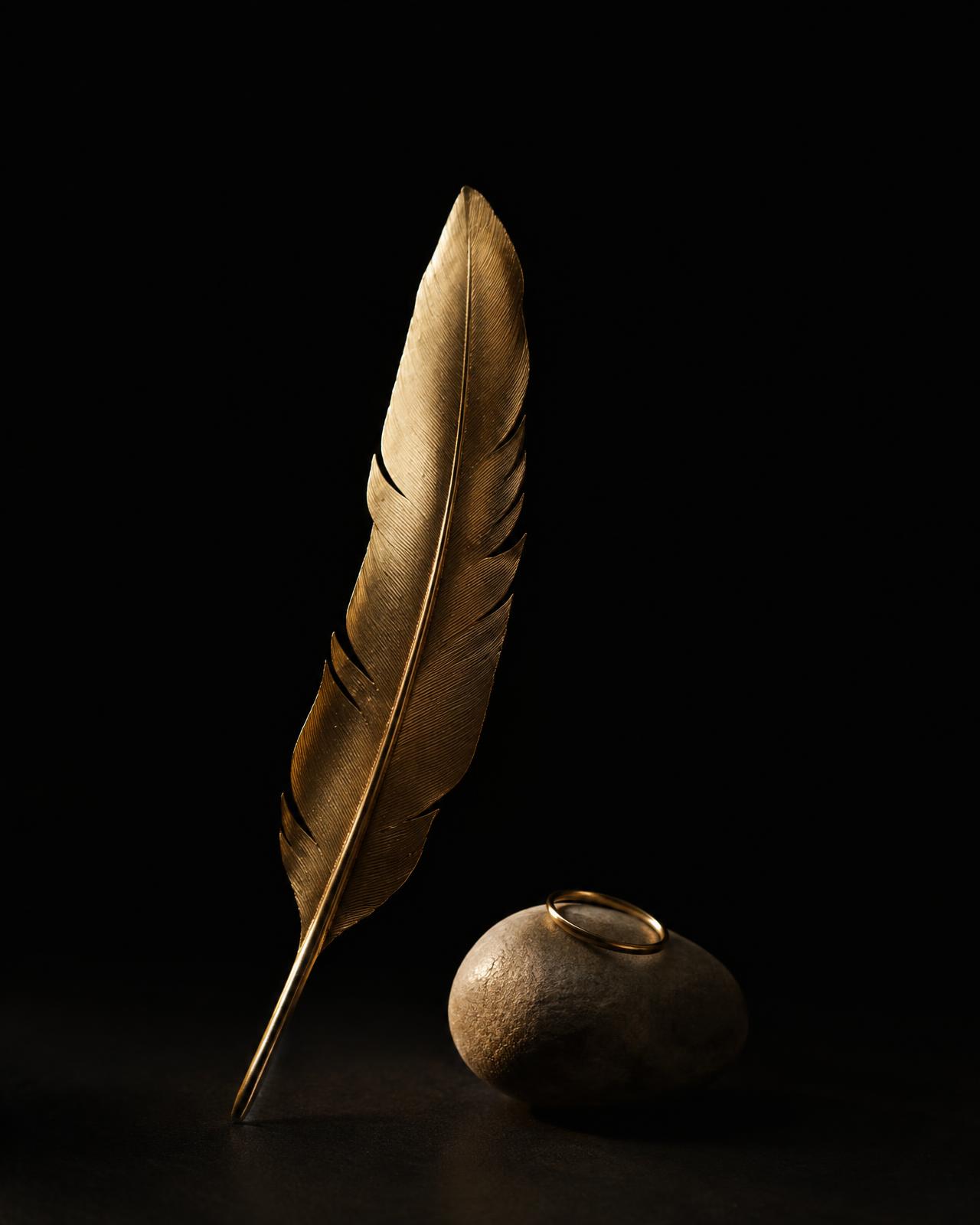 Pena dourada e pedra com anel de ouro